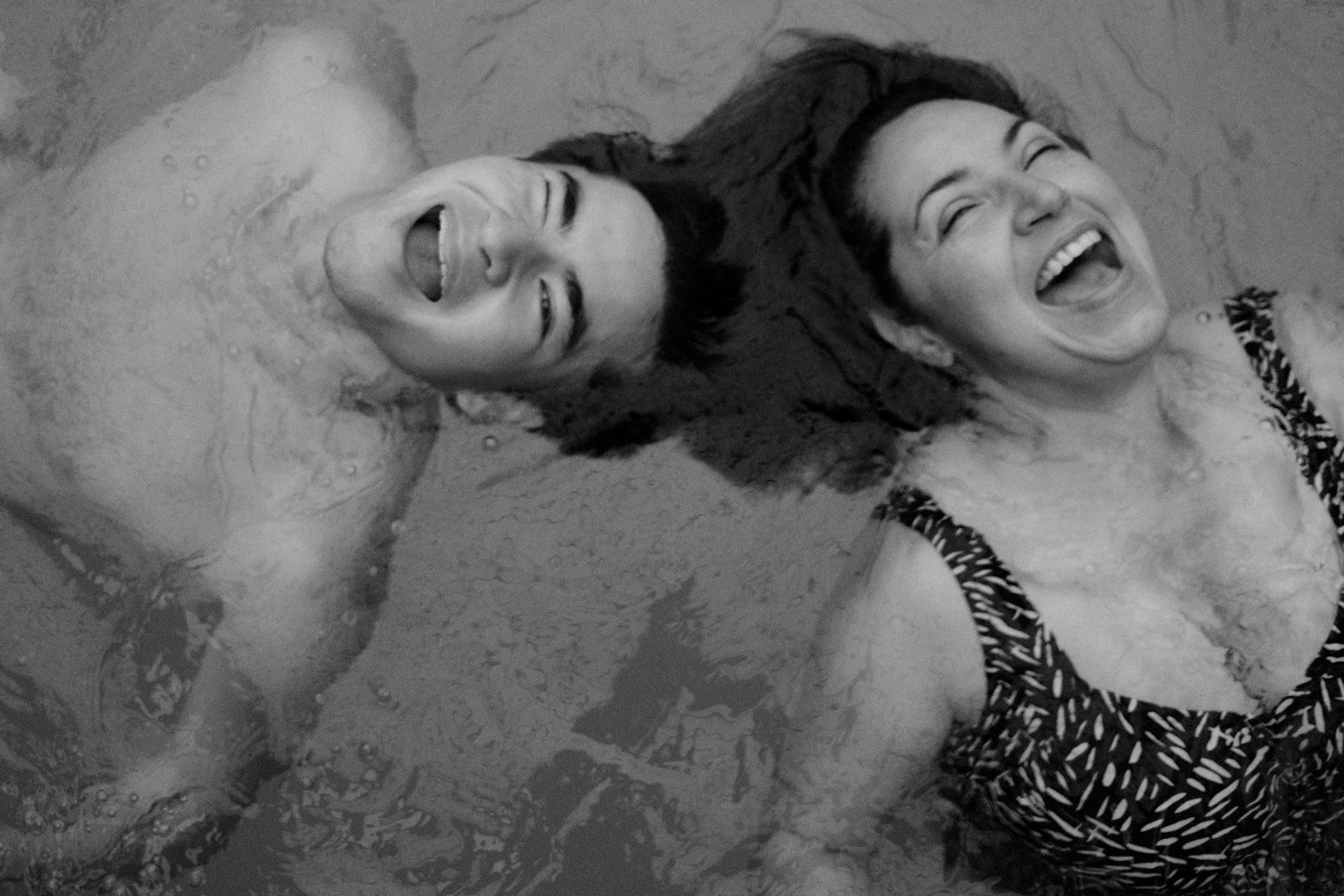 Image description: black-and-white image of the artist’s mother with her partner, laughing and looking at the sky while in a pool. Photo by Maryv Benoit.