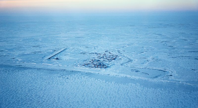 An aerial view of a small village in the middle of a flat landscape covered in snow and ice.