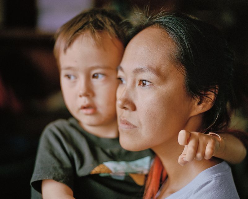 A woman in profile holds her young son.