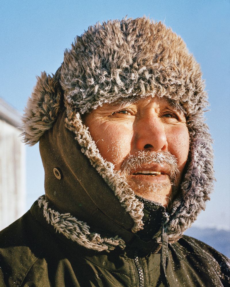 A close-up of a man’s head in a furry winter hat.