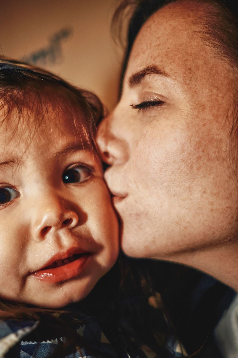 A close-up of a woman kissing a young child.