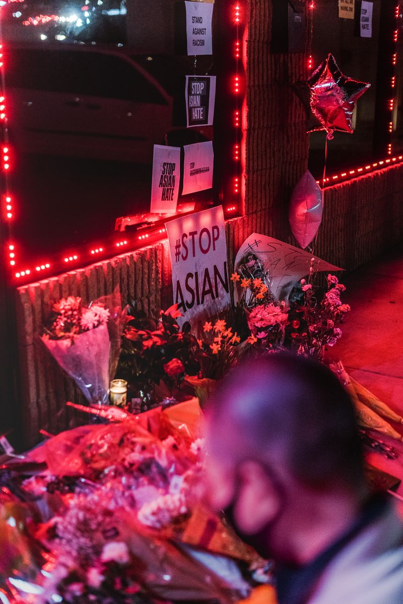 Un monumento en la acera con flores, globos y carteles sobre Detener el odio a los asiáticos.