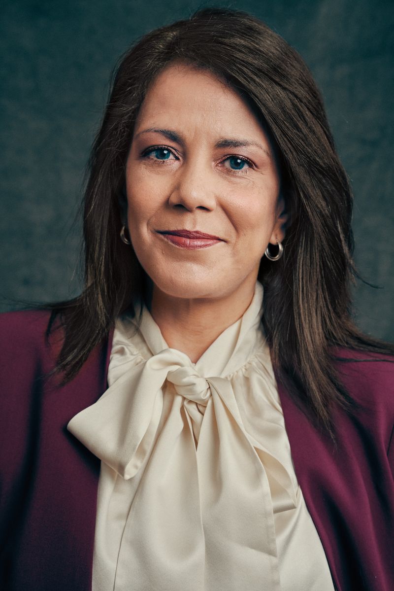 A headshot of a woman in a purple suit and white blouse.