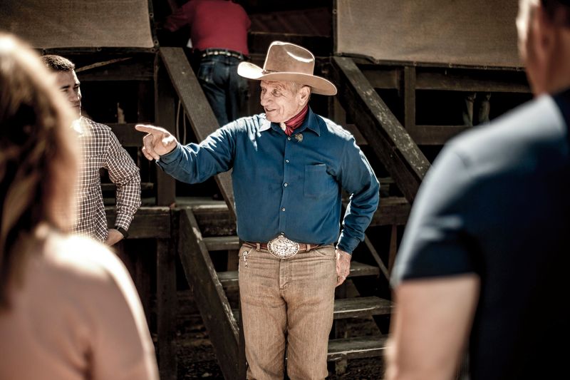 A man in a cowboy hat talks to a small group of people.