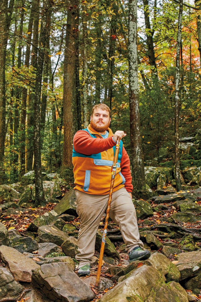 A man poses with a walking stick.