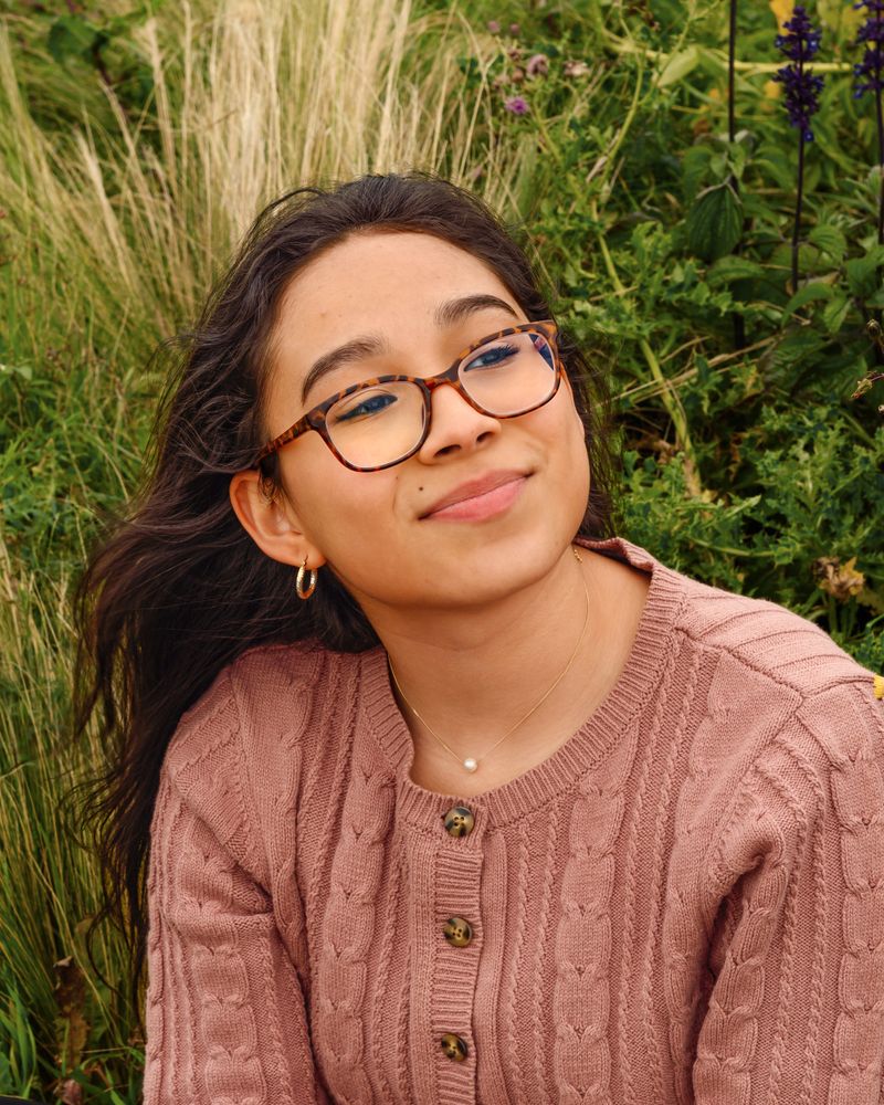 Una niña con lentes frente a las plantas